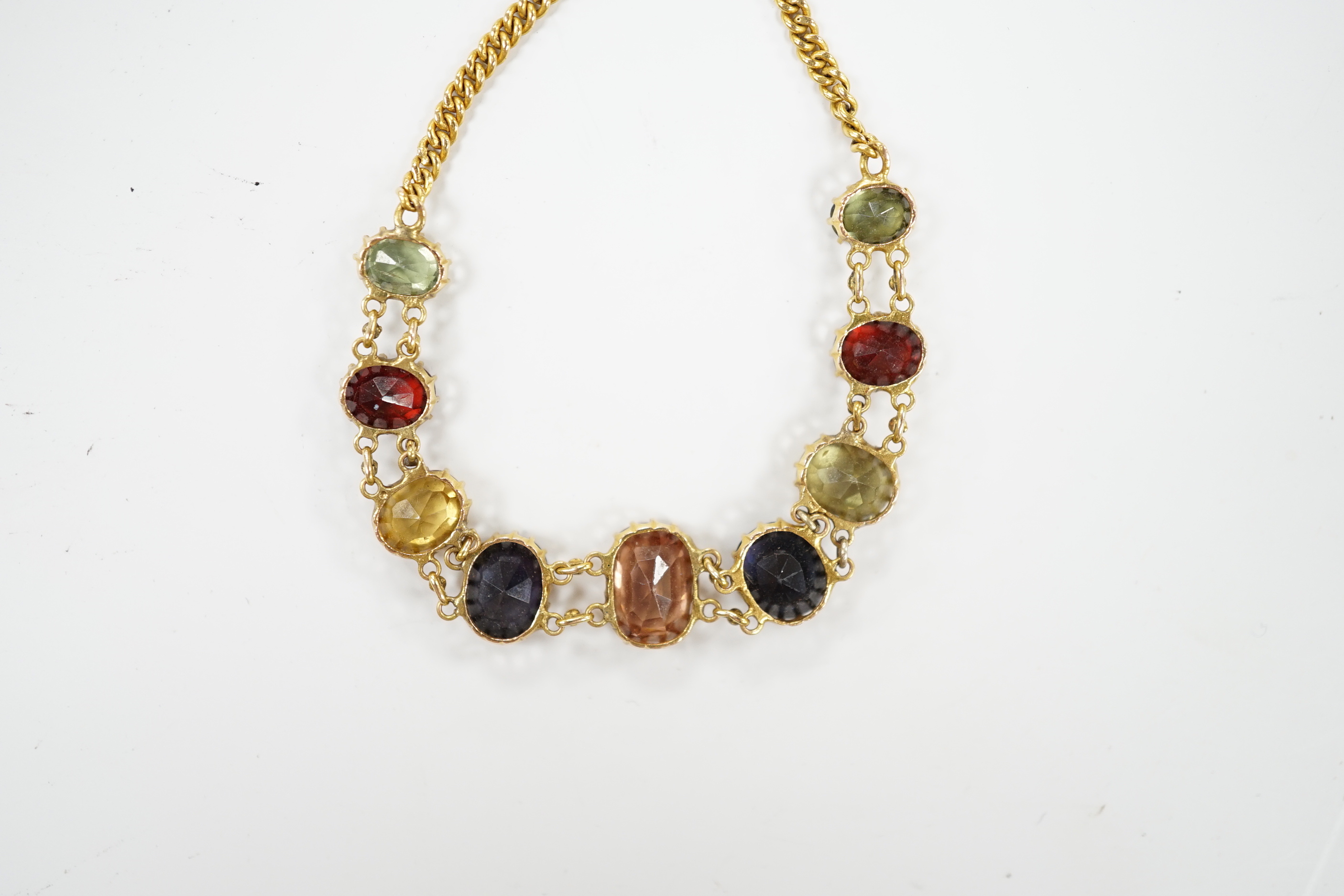 An early 20th century yellow metal and graduated multi-coloured oval cut zircon? set bracelet, 15.5cm, gross weight 7 grams.